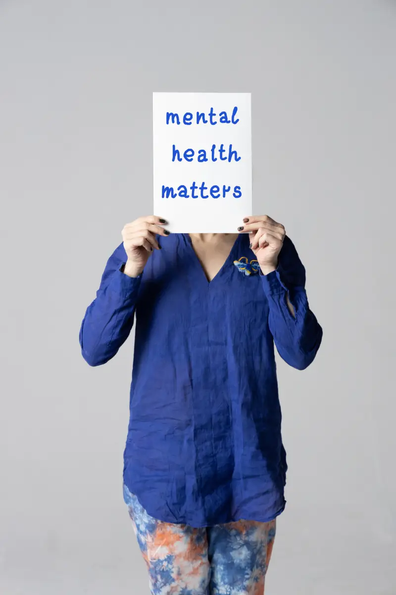 Woman covering her face with a white poster with the words mental health matter. Woman covering her face with a white poster with the words mental health matter.<br />